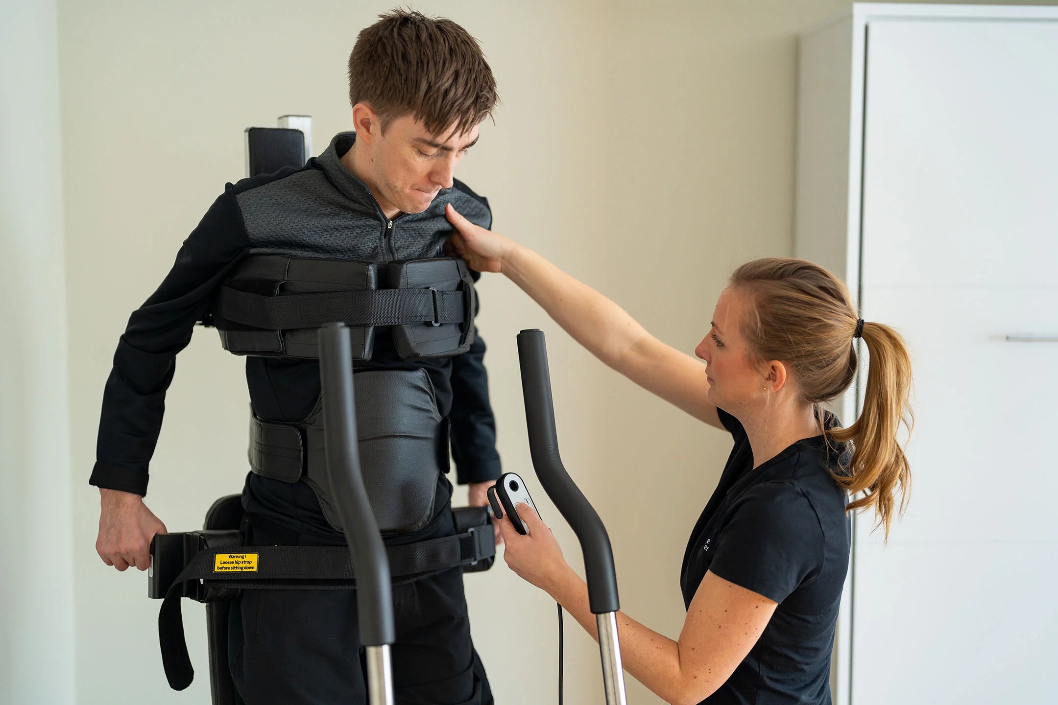 Adult standing in the Innowalk with a therapist guiding him